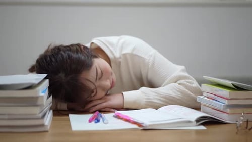 Exhausted Student Sleeping on Books at Desk