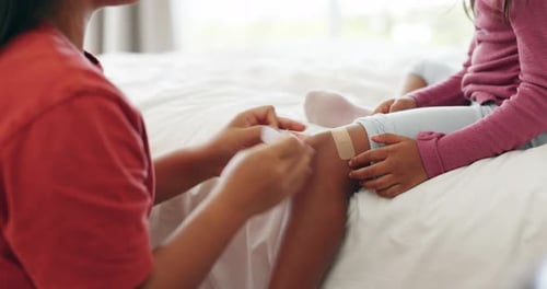 Adult Applying Bandage to Child's Knee at Home
