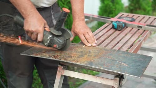 Worker cutting metal tube using an Angle Grinder. Bright sparks and flash