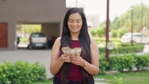 Woman Counting Money Outside of Suburban Home