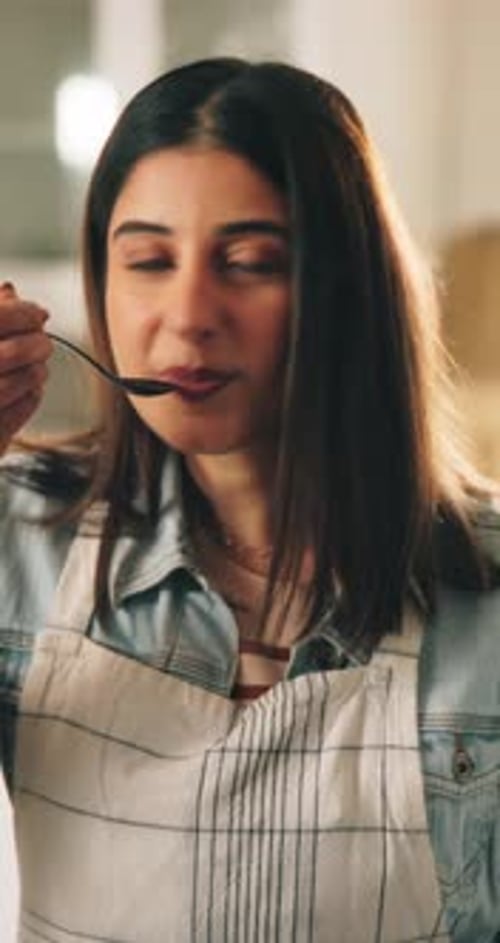 Young Woman Tasting Food with Spoon Indoors