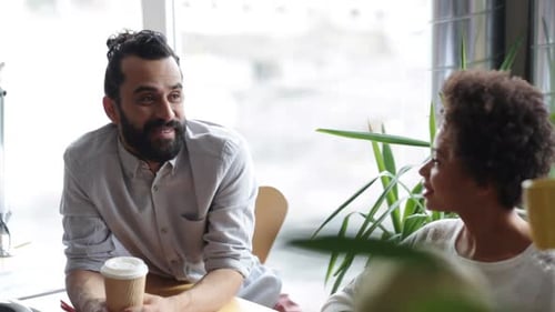 Happy multiethnic business team drinking coffee and chatting at office breaktime