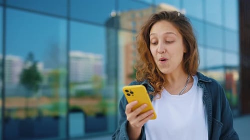 Woman Celebrates Good News on Mobile Phone in City