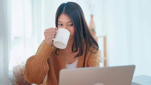 Young Woman Works on Laptop with Hot Drink