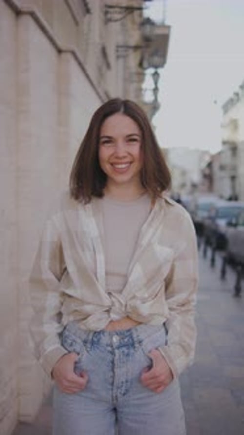 Vertical Portrait of a Young Beautiful Woman on the Street A Beautiful Girl Looks at the Camera and