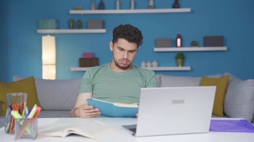 Man Studying at Desk With Book and Laptop