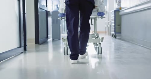Patient, bed and nurse walking in hospital with feet or steps in hallway or corridor to surgery