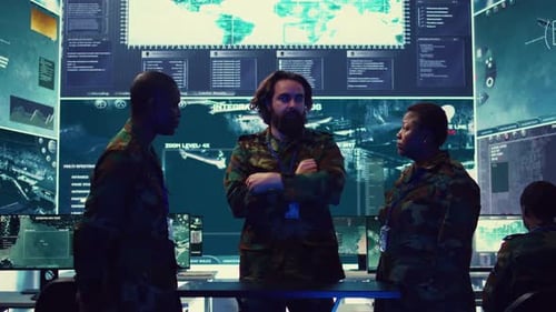Three People Discussing Strategy in a Control Room