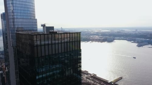 Ascending aerial view in front of high-rise in Hudson Yards, overlooking a ferry on the river