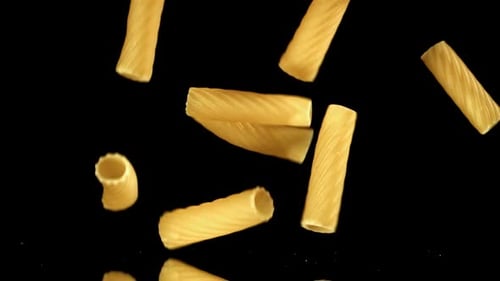 Delicious rigatoni pasta falling on black background for chroma