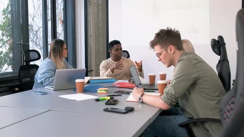 Diverse group of young people working on new project together in office.