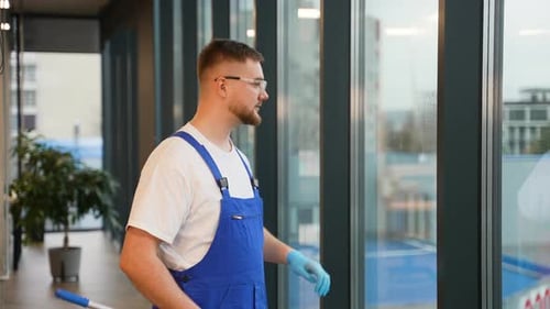 Concierge professionnel nettoyant les grandes fenêtres de bureau
