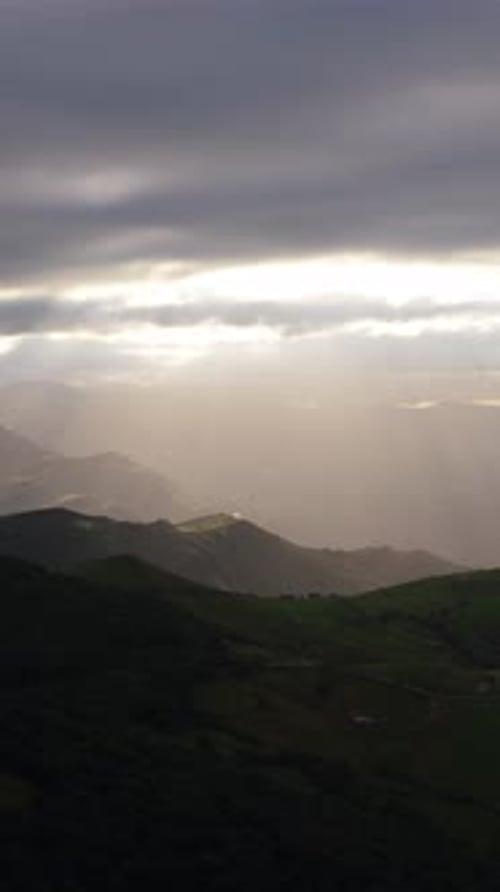 Dramáticos rayos de sol que brillan a través de las nubes sobre verdes montañas verticales