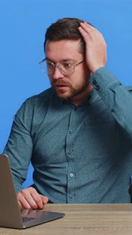 Man at Desk Reacting Negatively to Laptop