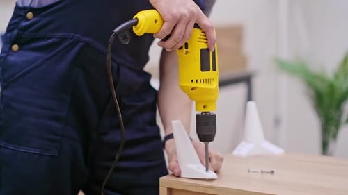 Man Attaches Furniture with Yellow Power Drill