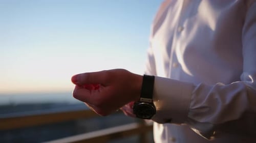 Man Adjusting Cufflinks at Sunset Preparation for Wedding