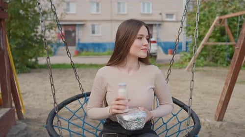 Relaxed Girl Enjoying Outdoors Casual Woman Swinging with Meal in Park Caucasian Female Enjoying