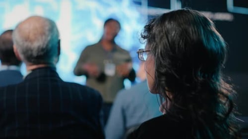Senior Female in Audience Listening to AI Sales Pitch Featuring Neural Networks
