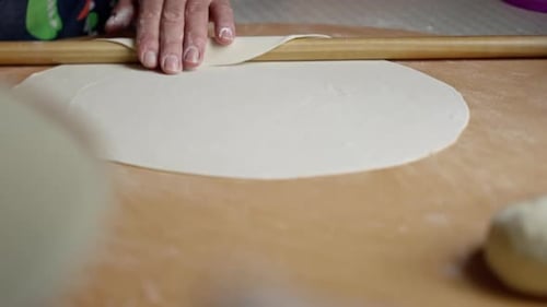 Hands Rolling Dough with a Rolling Pin
