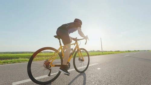 Cyclist in Sport Outfit Training on Bike Along Highway