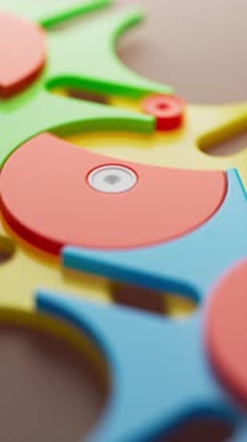 Looped rotation of colorful plastic gears in blue, yellow, green, and red.