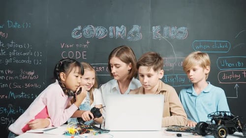 Smart teacher and diverse student looking at laptop at blackboard. Erudition.