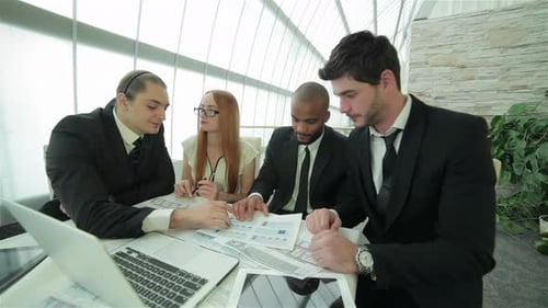 Four Smiling Successful Businessmen Sitting at Table in Office