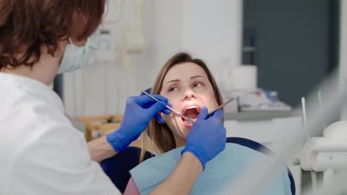 Woman receives dental checkup from dentist in modern clinic surgery
