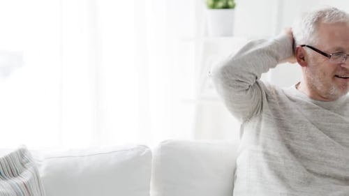 Senior Man Using Smartphone on Sofa Indoors