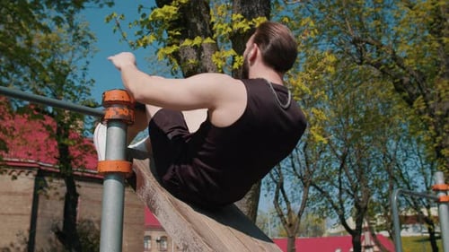Athletic Lebanese Man in Sportswear Training Abs Doing Abdominal Crunches on Playground Outdoors