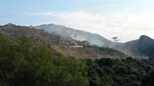 Airplane drops water on burning mountainside