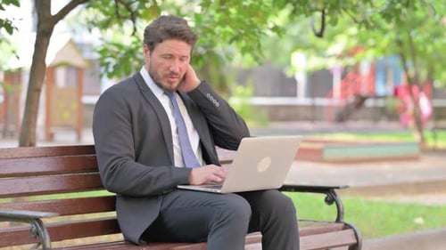 Man working on laptop in park setting