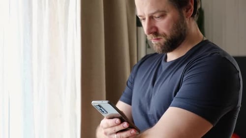Focused man using mobile phone at home