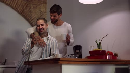 Two Young Adults Looking at Phone in Kitchen