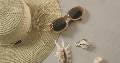 Beach Hat, Sunglasses, and Seashells on Grey Surface