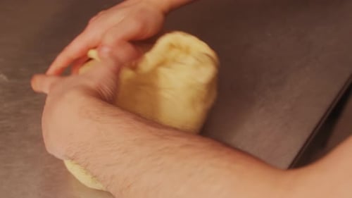 Hands Kneading Dough on Metal Countertop