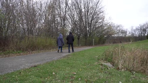 Ein Paar geht zusammen in einem Park auf einem Pfad mit wunderschönem Hintergrund spazieren. Dahinter sieht man eine