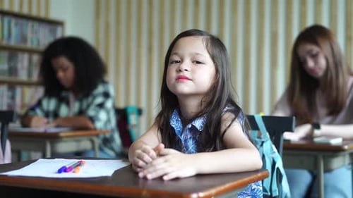 Child Student Sits at Desk in Classroom