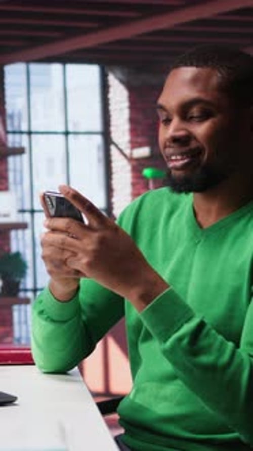 Vertikaler Videomann macht eine Pause von der Arbeit, um seine Social-Media-Apps auf dem Handy zu überprüfen