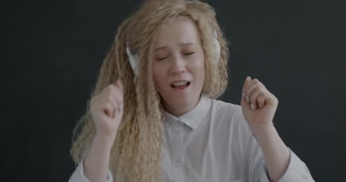 Slow Motion Portrait of Cheerful Young Woman Listening to Music with Headphones Dancing