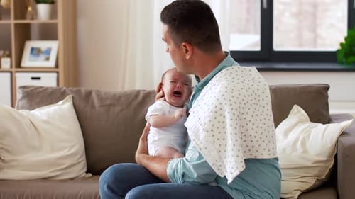 Family, Parenthood And Fatherhood Concept - Middle Aged Father Comforting Crying Little Baby Daug...