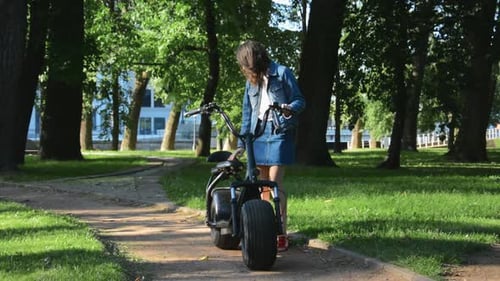 Woman Sitting on Electric Scooter in Park