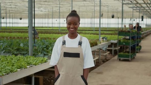 Woman Smiling in a Greenhouse Filled With Crops