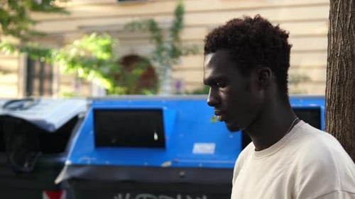 Man Leaning Against Tree in Urban Setting