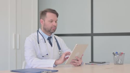 Doctor Using Tablet at His Desk in Office