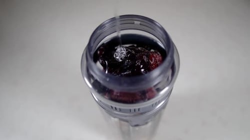 Verser le sirop transparent dans un bocal rempli de baies mélangées, SLOW MOTION