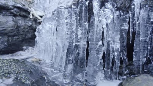 Imagen de una cascada congelada con carámbanos puntiagudos. Movimiento panorámico hacia la derecha.