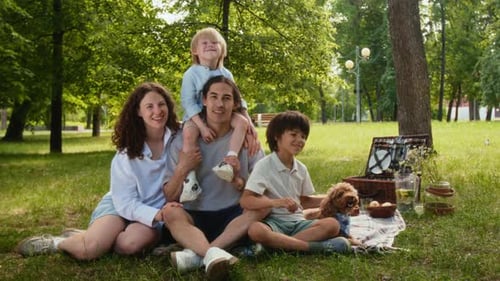 Portrait of Joyful Family and Their Dog Having Picnic in Park