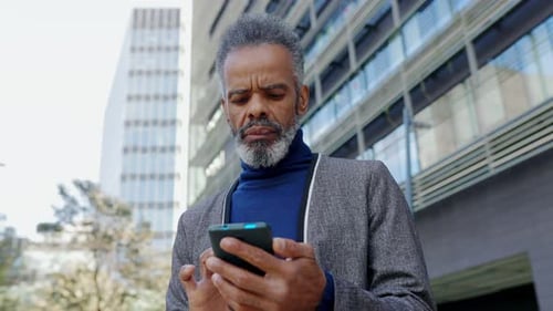 Adult Using Smartphone in Front of Buildings