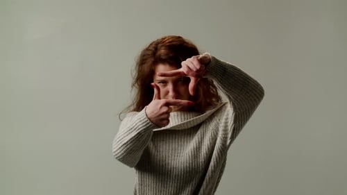 Woman Frames Face with Hands in Studio